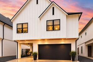 Ein zweistöckiges Haus mit Garage, großen Fenstern und Auffahrt.