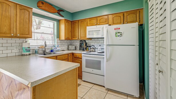 Una cocina con armarios de madera, un refrigerador blanco, un microondas y una estufa.