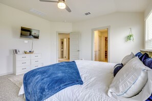 Ein Schlafzimmer mit einem Bett, einem Fernseher, einem Schminktisch und einem Deckenventilator.
