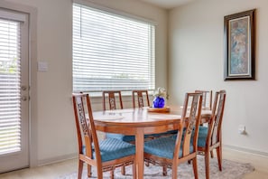 A dining area with a wooden table, six chairs, and a vase with flowers. - Fenced Yard! Family Getaway, Near Texas Ski Ranch (San Marcos)