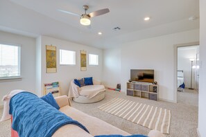 Ein modernes Wohnzimmer mit Deckenventilator, Flachbildfernseher und Bücherregal.
