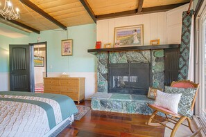 A cozy room with a bed, a rocking chair, a fireplace, and a chandelier. - Lake Arrowhead Retreat w/ Game Loft & Media Room (Lake Arrowhead)