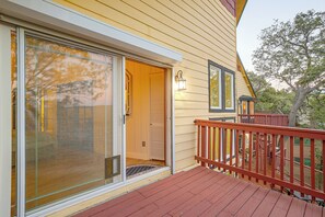A wooden house with a sliding glass door, a red deck, and a small porch with a railing. - Lake Arrowhead Retreat w/ Game Loft & Media Room (Lake Arrowhead)