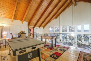 A room with a foosball table, a dining table with chairs, and a view through a window. - Lake Arrowhead Retreat w/ Game Loft & Media Room (Lake Arrowhead)