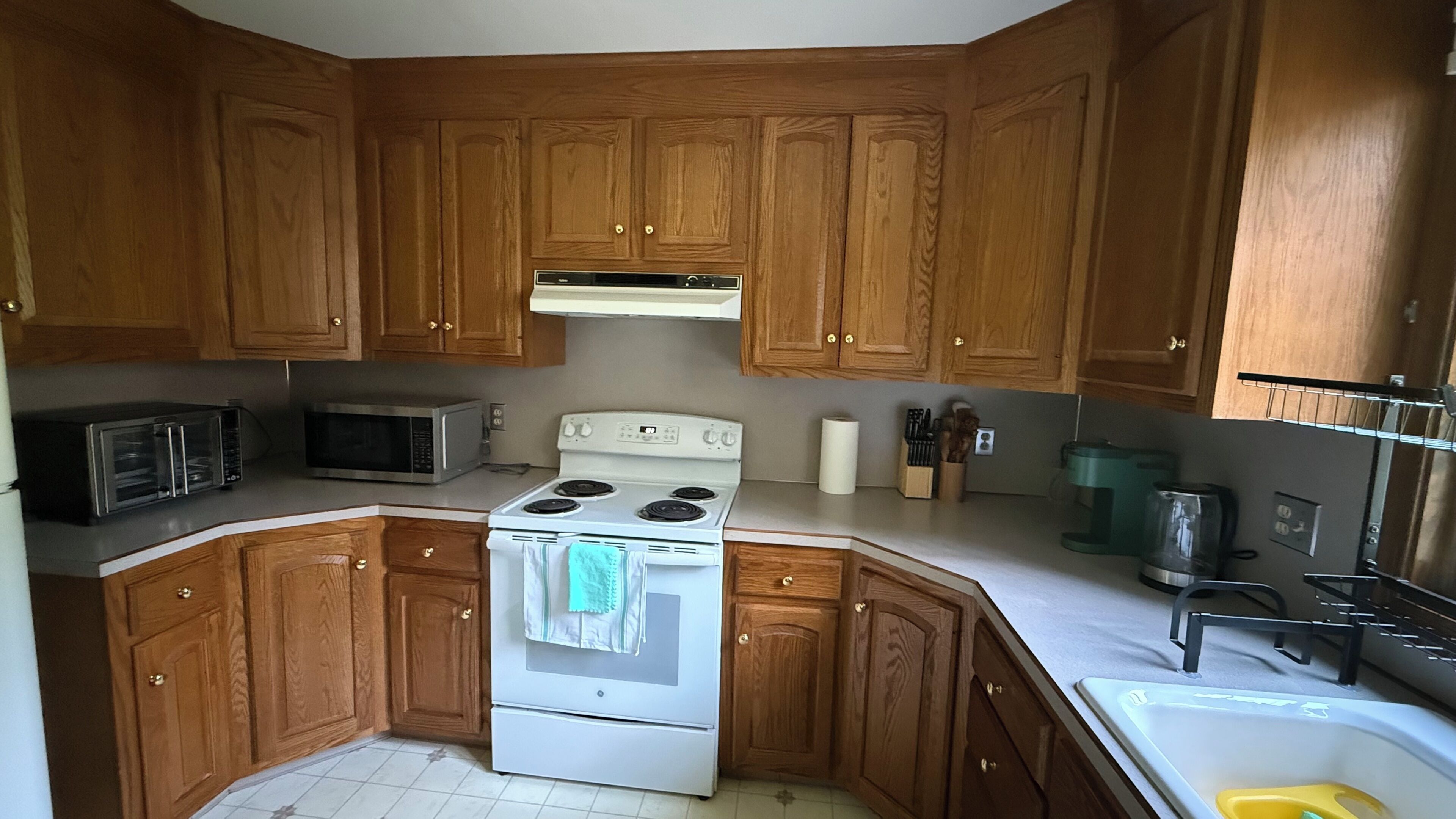 A kitchen with wooden cabinets, a microwave, a stove, and a sink.