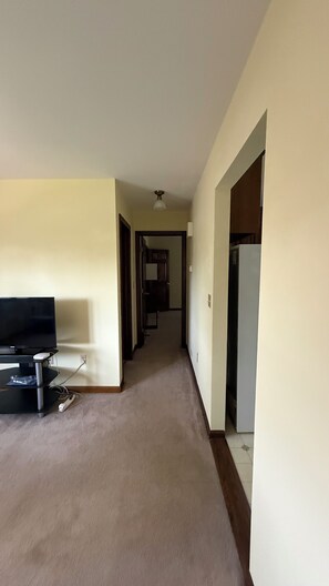 Ein Flur mit Fernseher, Deckenventilator und Kühlschrank.
