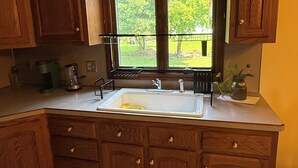 A kitchen with wooden cabinets, a stainless steel sink, and a window with a view of greenery. - Cozy 1-bedroom In-law apartment in cool Middletown with AC (Middletown)