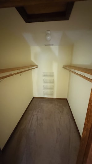 A room with a sloped ceiling, wooden beams, and a light fixture. There are two wooden shelves on the walls. - Cozy 1-bedroom In-law apartment in cool Middletown with AC (Middletown)