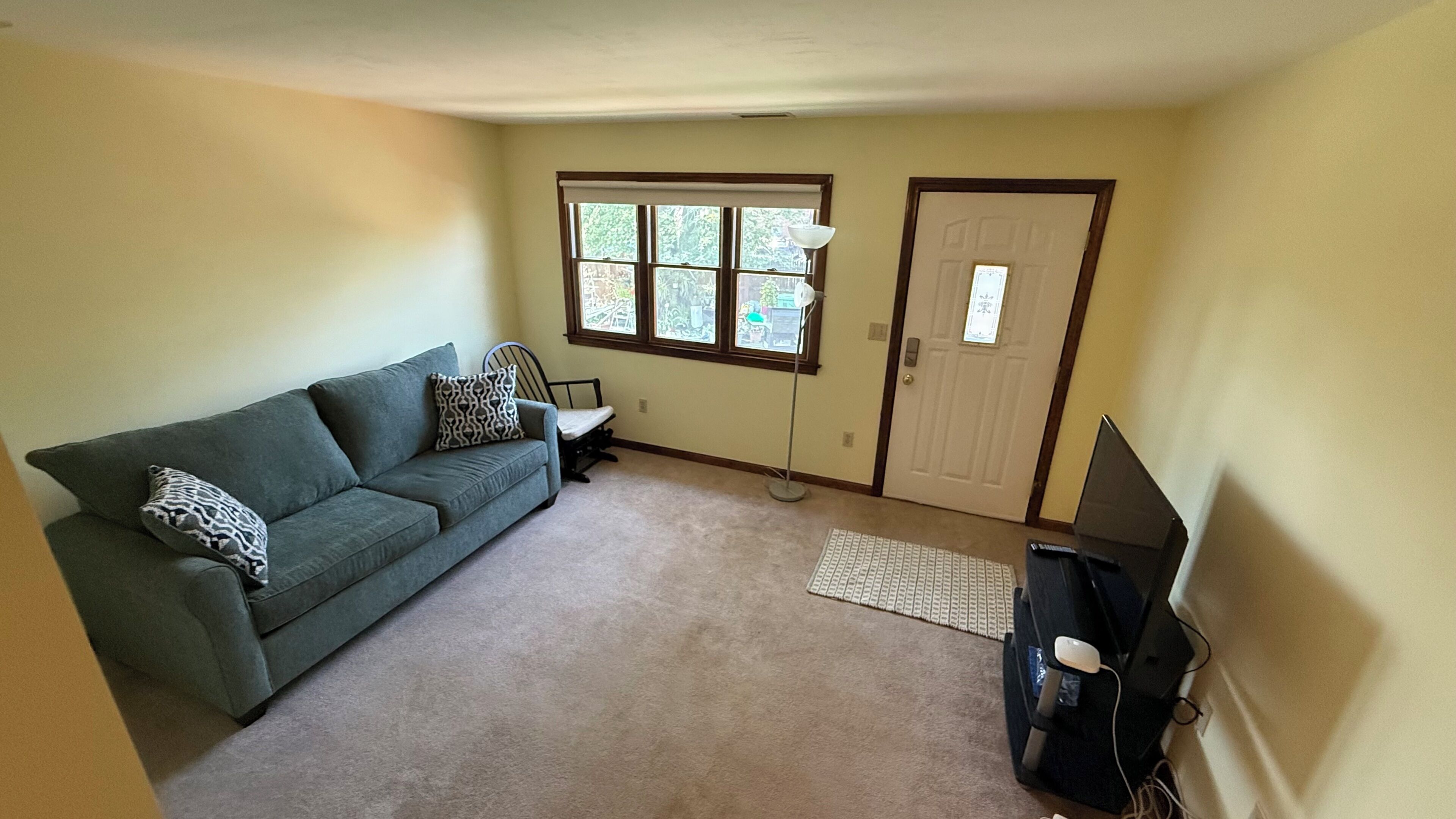 A room with a green sofa, a desk, a computer, and a door.