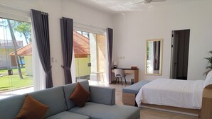 Habitación de hotel moderna con sofá, cama, escritorio y vista a un edificio de techo rojo.