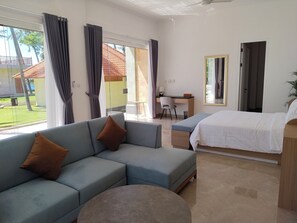 Habitación de hotel moderna con sofá, cama, escritorio y vista a un edificio de techo rojo.
