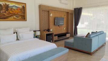 Quarto de hotel com cama, sofá, televisão e um quadro na parede.
