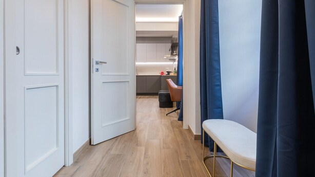 Ein Flur, der zu einem Zimmer mit einem Bett, einem Sessel und einem Schreibtisch führt.