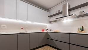Eine moderne Küche mit grauen Schränken, einer Edelstahl-Dunstabzugshaube und einem Holzboden.
