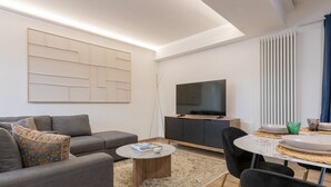 Ein modernes Wohnzimmer mit Sofa, Couchtisch, Fernseher und Essbereich.