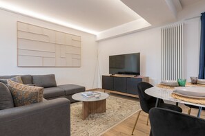 Ein modernes Wohnzimmer mit Sofa, Couchtisch, Fernseher und Essbereich.