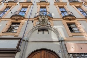 A building facade with a central arched entrance, multiple windows, and balconies with ornate railings. - Milano Modern Home by Wonderful Italy (Turin)