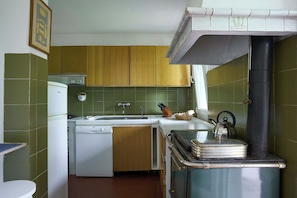 A compact kitchen with wooden cabinets, a white dishwasher, and a sink.