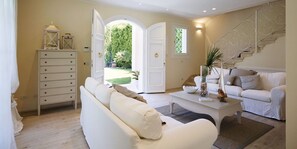 Ein Wohnzimmer mit weißem Sofa, Couchtisch und Wendeltreppe.