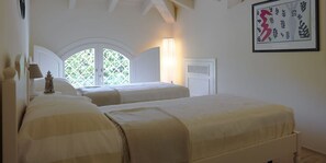 A bedroom with two beds, a window with a view of greenery, a framed artwork on the wall, and a lamp on the nightstand. - The Pool Villa In Forte dei Marmi (Forte Dei Marmi)