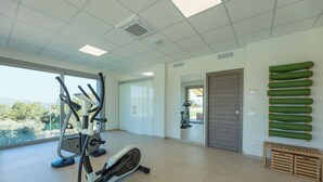 Ein Fitnessraum mit Trainingsgeräten, Blick durch das Fenster und einer Tür zu einem anderen Raum.