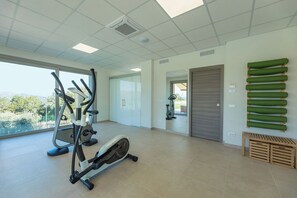 Ein Fitnessraum mit Trainingsgeräten, Blick durch das Fenster und einer Tür zu einem anderen Raum.