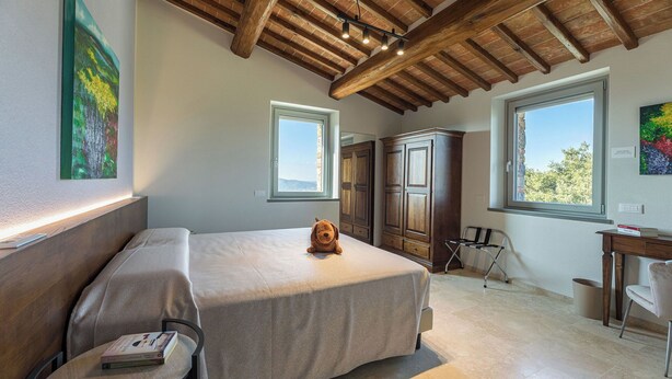 Ein Schlafzimmer mit Bett, Schreibtisch und Kleiderschrank. Fenster sorgen für natürliches Licht.