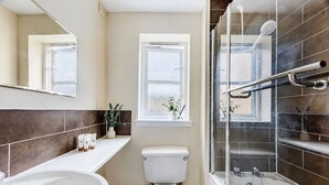 Un baño moderno con bañera, inodoro y zona de ducha.
