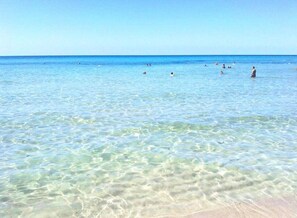 Ein Strand mit klarem, flachen Wasser und einem Sandufer.