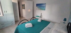 Ein Zimmer mit einem Bett, einem Sessel, einem Tisch und einem Bild an der Wand.