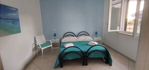 Ein Schlafzimmer mit einem Bett, zwei Nachttischen, einem Sessel, einem Fenster und einem Bild an der Wand.