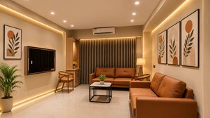 A modern living room with a sofa, a coffee table, a TV, and artwork on the walls.