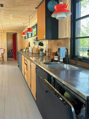 Eine moderne Küche mit Holzschränken, einer Edelstahl-Arbeitsfläche und einem großen Fenster für natürliches Licht.