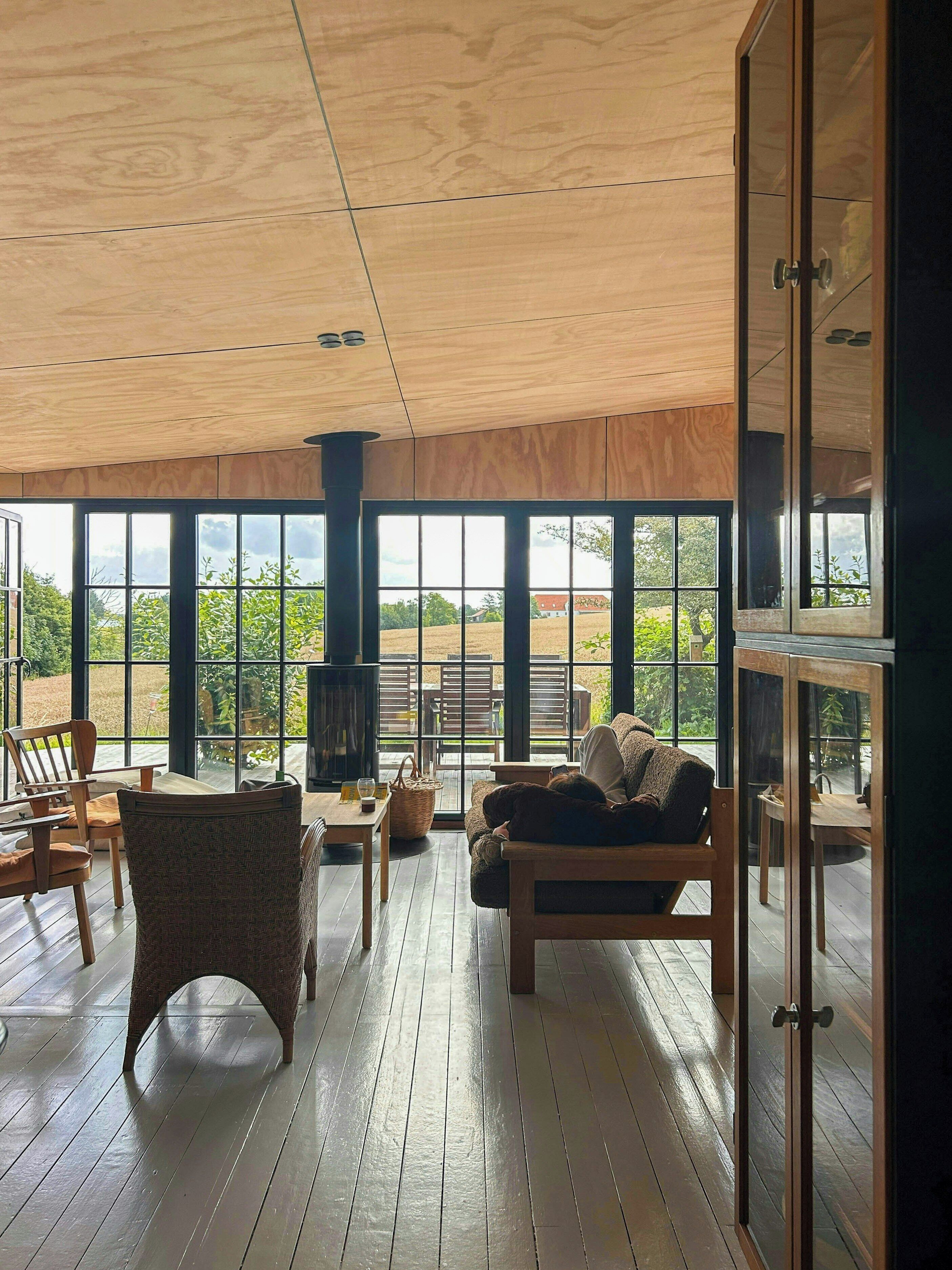 Une pièce spacieuse dotée de grandes fenêtres, d’un plancher en bois et d’un coin salon confortable avec une cheminée.