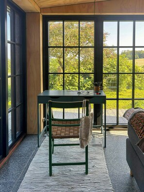 A room with a large window, a desk, a chair, and a sofa. - Beach house with sea view in Røsnæs (Kalundborg)