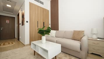 Una sala moderna con un sofá, una mesita auxiliar blanca, una planta en maceta y una lámpara.