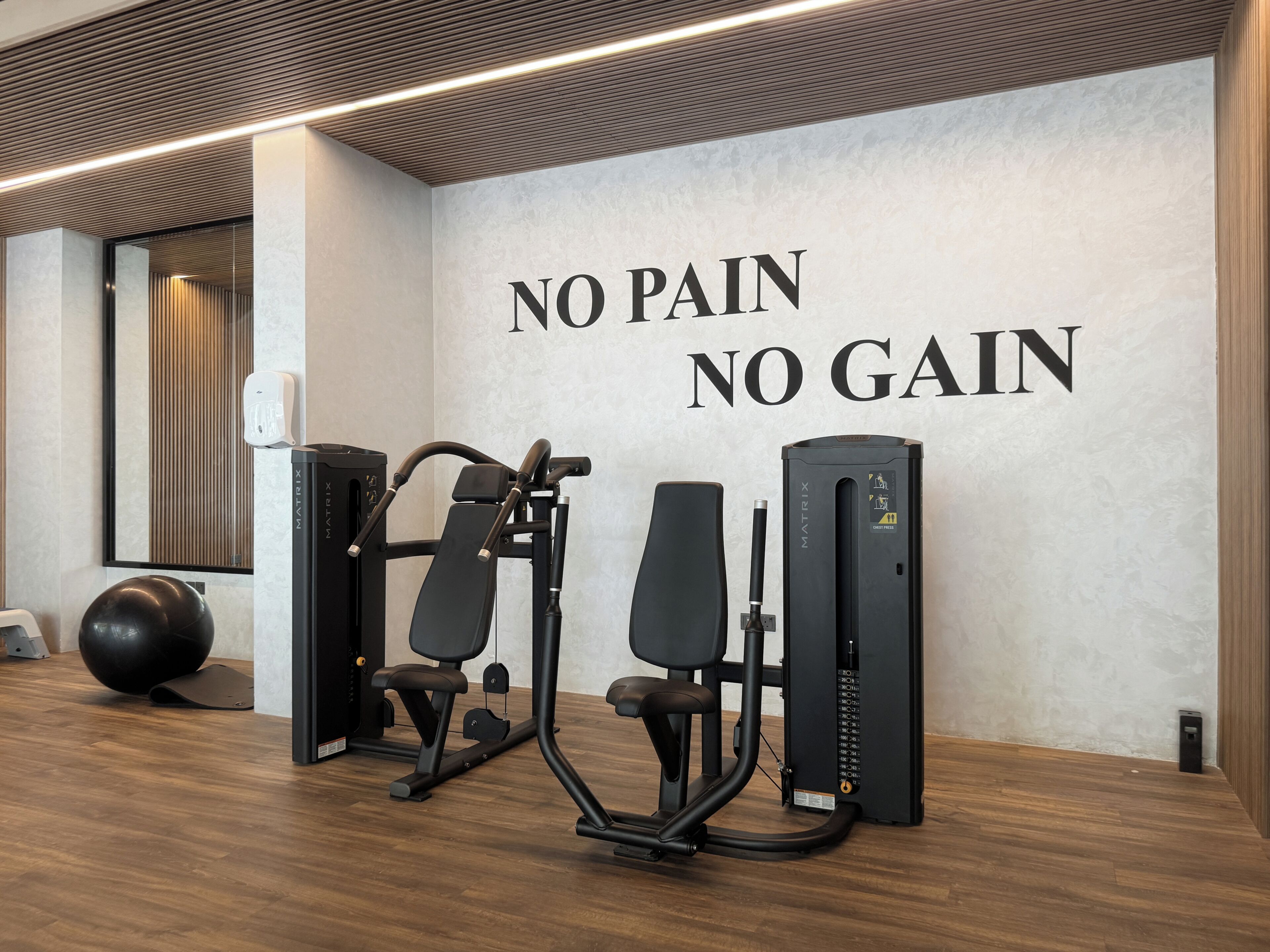A gym with exercise equipment and a motivational wall saying 'NO PAIN NO GAIN'.