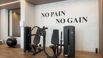 Un gimnasio con equipo de ejercicio y una pared con el lema 'NO PAIN NO GAIN'.