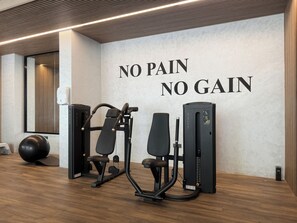 A gym with exercise equipment and a motivational wall saying 'NO PAIN NO GAIN'. - Bloomfields Studio in Elysee 3 (Dubai)