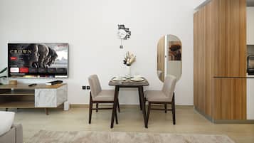 Una sala de estar moderna con una mesa de comedor, sillas, un televisor y un aparador de madera.