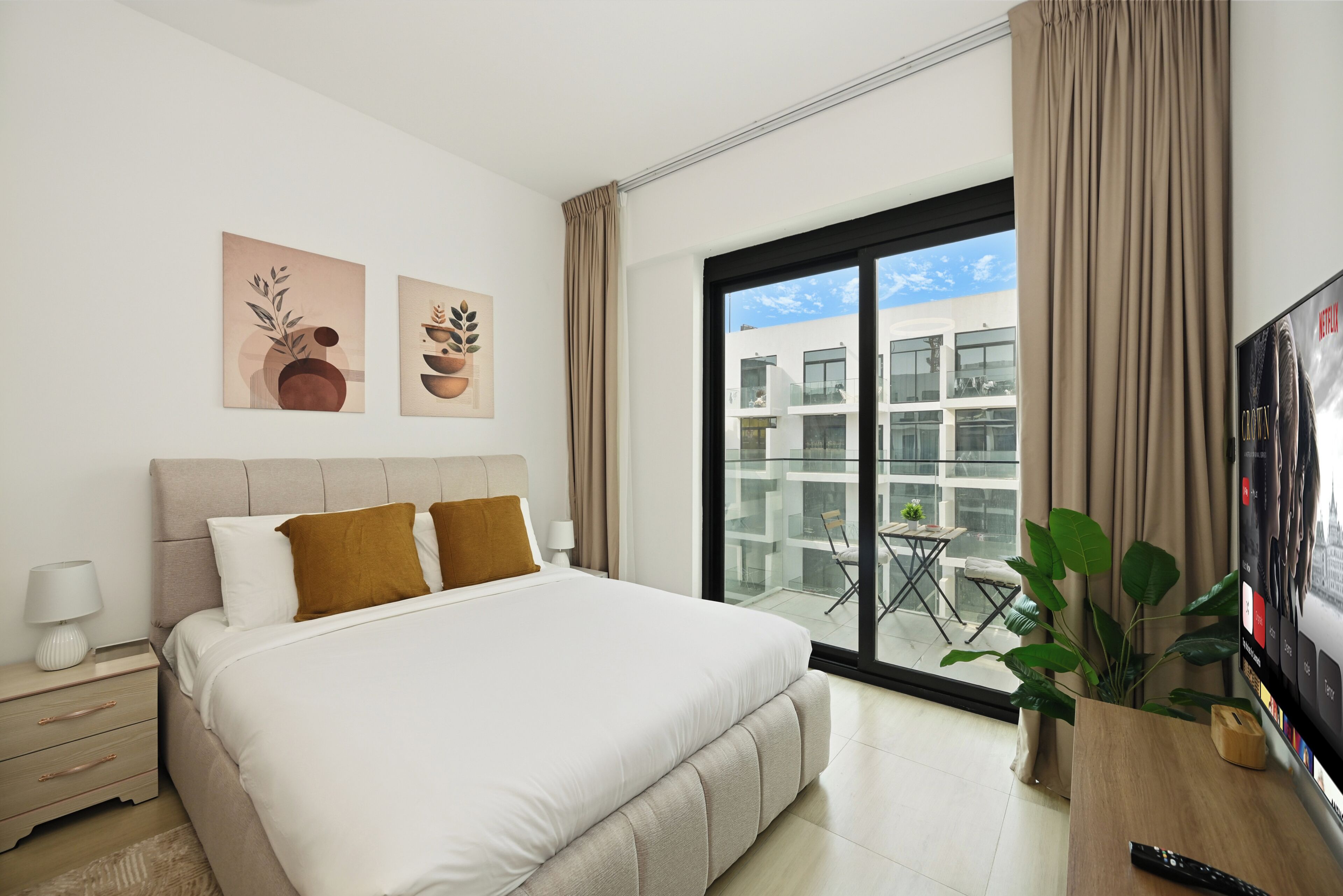 Habitación de hotel moderna con una cama grande, televisión y balcón con vista a la ciudad.