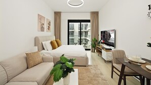 Ein modernes Hotelzimmer mit Bett, Sofa, Esstisch und Fernseher.