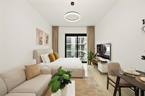 A modern hotel room with a bed, sofa, dining table, and a TV. - Bloomfields Studio in Elysee 3 (Dubai)