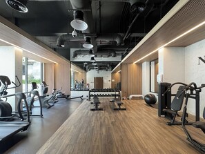 A gym with treadmills, dumbbells, and weight plates. - Bloomfields Studio in Elysee 3 by Pantheon (Dubai)