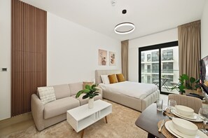 A modern hotel room with a sofa, a bed, a coffee table, and a dining area. - Bloomfields Studio in Elysee 3 (Dubai)