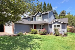 A two-story house with a front porch, a garage, and a well-maintained lawn. - Peaceful 5-Bed Home at Road's End by Woods & Berry Farm, near Parks & Intel/Nike (Hillsboro)