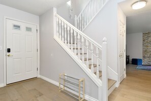 A staircase with white balusters and a handrail, leading to a landing with a door and a small window. - Peaceful 5-Bed Home at Road's End by Woods & Berry Farm, near Parks & Intel/Nike (Hillsboro)