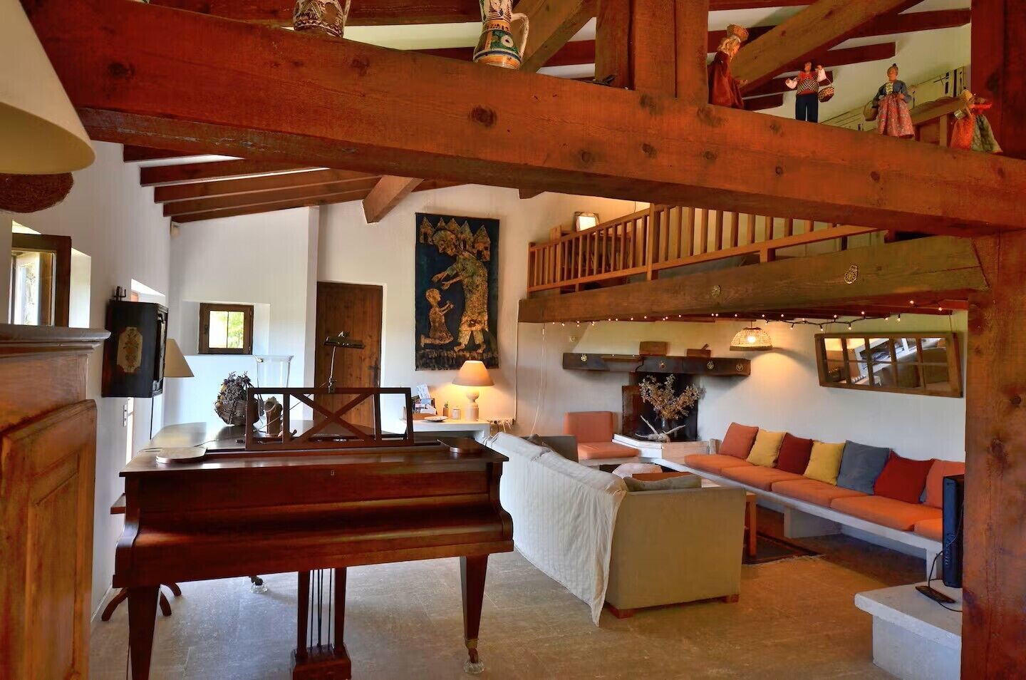 Une pièce spacieuse avec un plafond en bois, un piano, un ensemble de canapés et une cheminée.