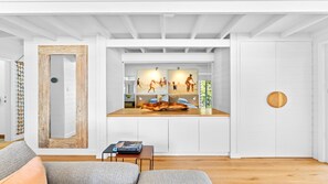 Ein modernes Interieur mit Holzboden, einem großen Spiegel, einer Couch und einer Wand mit gerahmten Kunstwerken.