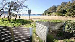 Ein Zugang zum Strand mit Holztoren, einem Wegweiser und Blick auf den Strand und das Meer.